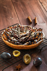 Plum pie on a stand for hot, next to plums and star anise