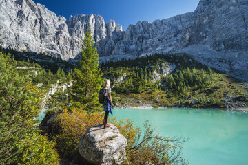 Woman hiker enjozing beautifulturquoise mountain Sorapiss lake in Dolomites, Italy