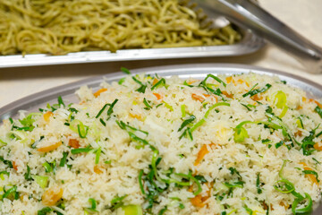 Pratos com arroz e macarrão em mesa de bufê para festa de aniversário.