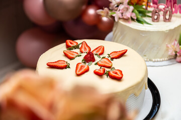 Bolo decorado com glacê e morango em uma mesa decorada para uma festa de aniversário.