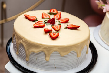 Bolo decorado com glacê e morango em uma mesa decorada para uma festa de aniversário.