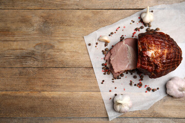 Cut delicious ham, spices and garlic on wooden table, flat lay. Space for text