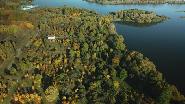 Flight over the autumn park. Trees with yellow autumn leaves are visible. Park on the shore of a large lake. Aerial photography.