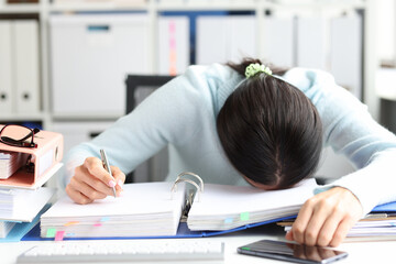 Tired woman lies on folder with documents on table in office