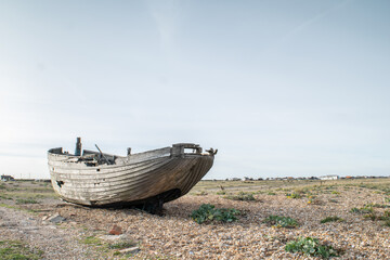 Abandoned and damaged wooden fishing boat wreck at the beach of Dungeness, Kent, England