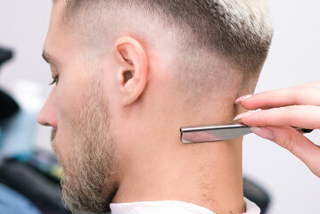 straight razor. haircut process of blond young man in barbershop salon, barbershop concept