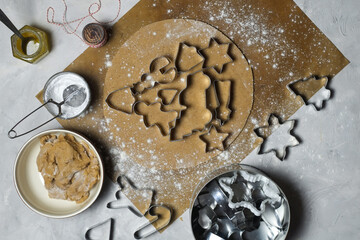Raw dough for cookies and cookie cutters on the light background. Christmas tree made of cookie cutters surrounded by kitchen utensils. flat lay .Preparing ginger cookies on Christmas Eve
