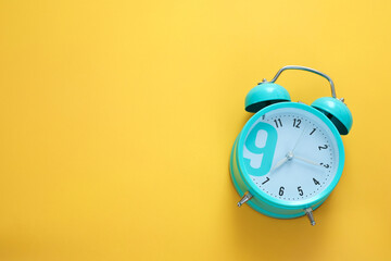 Blue alarm clock on the yellow background. Morning, time to wake up. Free space, copy space.