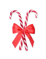 Sweet Christmas candy canes with red bow on white background, top view
