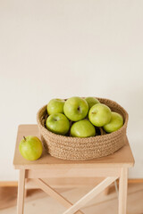 Ripe green apples in a handmade jute basket. Minimalistic home design. Cozy modern natural interior details.