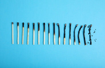Different stages of burnt matches on light blue background, flat lay