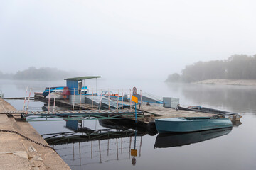 Fishing boats, small boats, moored to the pier in thick fog.
