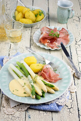 Traditional German white and green asparagus with prosciutto ham and boiled potatoes served as close-up on a Nordic design plate
