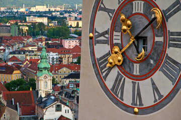 Landmark clocktower in Graz with huge clock and the citycentre in the back
