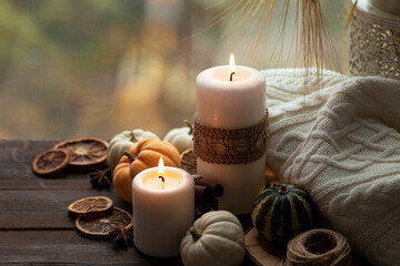 Fototapeta na wymiar Autumn composition with candles, mini munchkin pumpkins, warm wool knitted plaid on the wooden wind sill. Dark colors, low key. Cozy home atmosphere, Thanksgiving decor, fall colors. Close up
