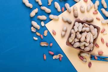 fresh peanuts in a shell on a bright blue slate, concrete or stone background. lots of nuts. the concept of proper nutrition. top view.