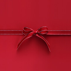 merry christmas gift card with red fabric ribbon bow isolated on red background, top view and copy...