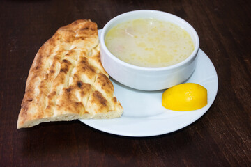 Turkish Traditional chicken Soup with bread and lemon on brown wooden background
