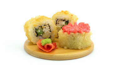 Still life with hot fried set sushi rolls on a round wooden plate isolated on white background. Cheap tempura roll with chicken, cucumber and pink mayonnaise