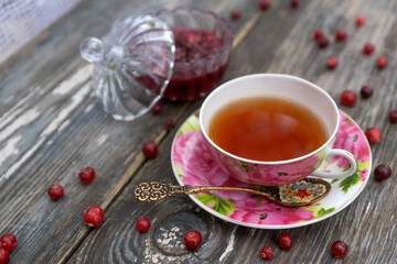 Tea in a beautiful cup and cranberry marmalade in the autumn garden.