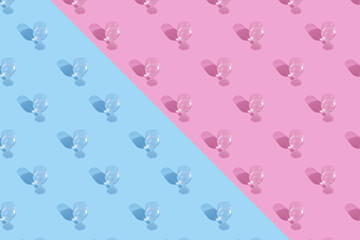 Glasses with water and shadow pattern on blue-pink background