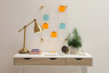 Memo board with colorful notes hanging on white wall over desk indoors
