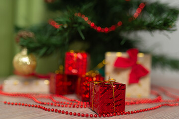 Small red box with a gift on the background of a Christmas tree