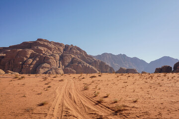 Fototapeta na wymiar an empty road in the Wadi Rum desert, beautiful red relief mountains are on the horizon, blue cloudless sky, nature of Jordan