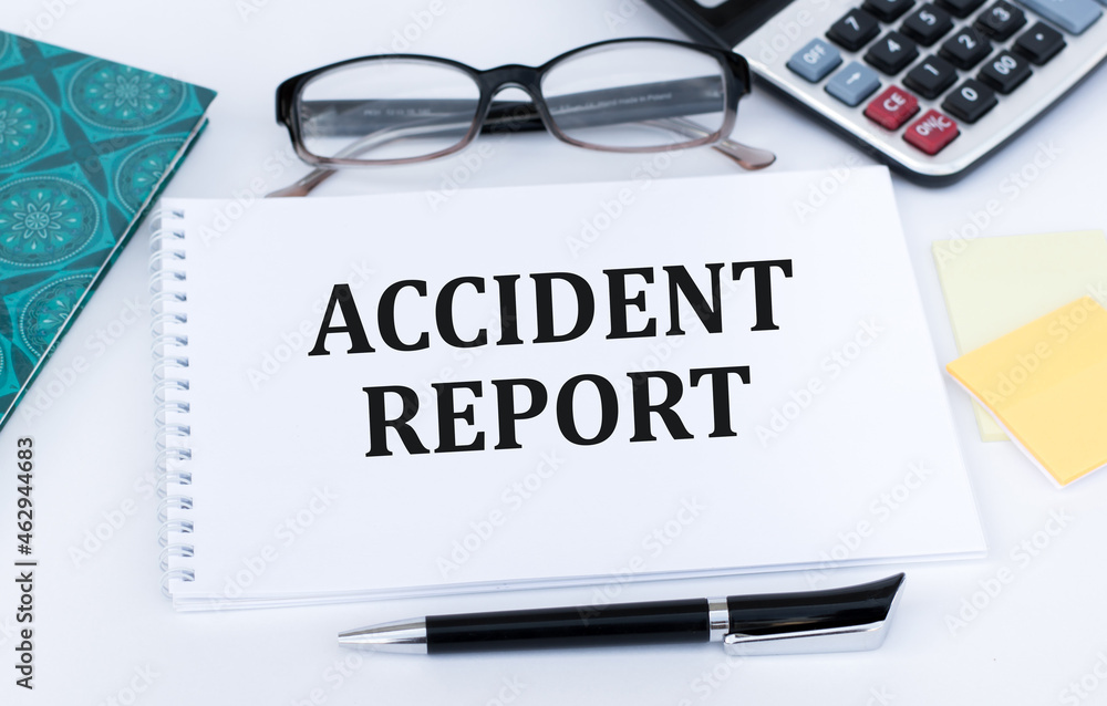 Poster notepad with text accident report on a white background next to glasses, calculator on the table