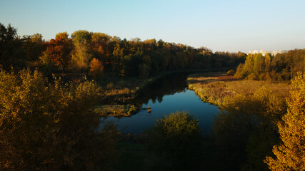 Park area. A winding river with water lilies. Trees with yellow autumn leaves are visible. Aerial photography.