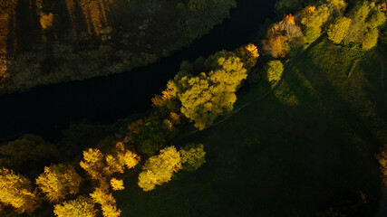 Park area. A winding river with water lilies. Trees with yellow autumn leaves are visible. Aerial photography.