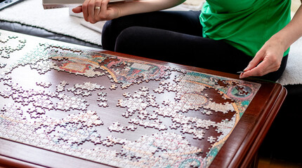 Woman's hands putting jigsaw puzzle pieces together. Home alone. Quarantine in Coronavirus outbreak.