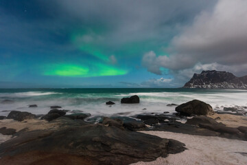 Beautiful Northern Lights in Lofoten Island in Norway. Aurora Boreal over the beach. Majestic green night sky.  Nightscape full os stars.