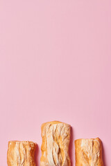 Three fresh homemade ciabatta breads on pink background with copy space. Vertical photograph.
