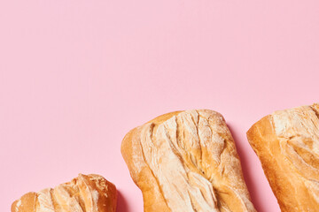 Three fresh homemade ciabatta breads on pink background with copy space. Horizontal photograph.
