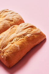 Close up of three fresh homemade ciabatta breads on pink background with copy space. Vertical photograph.