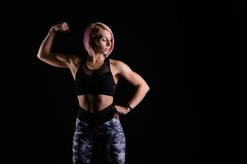 Obraz na płótnie Canvas Stylish sports Black background. Sport modern woman exercising strong with muscles. fitness banner. Workout gym. Girl powerful in sportswear. Bodybuilding. Pink hair. fitness motivation