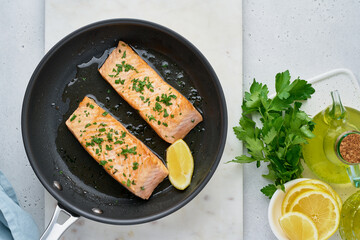 Juicy salmon fillet fried on pan with parsley, oil olive and lemon. Flavorful pescetarian meal. Healthy and dietary fish dish full of omega and fats. Overhead, horizontal