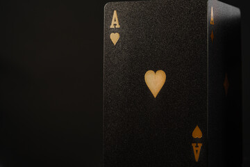 Black poker card - an ace of hearts with gold embossing on a plain black background. Minimalism. There are no people in the photo. Casino, online casino, night club, gambling business. - Powered by Adobe
