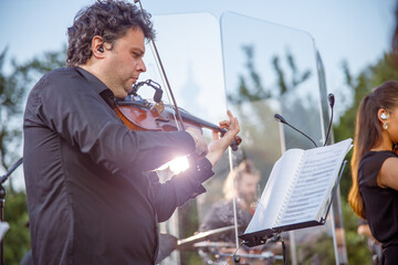Male violinist playing in orchestra on the street