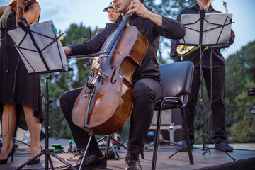 Male musician playing violoncello in orchestra on the street