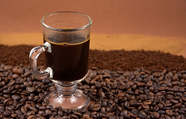 Cup of black hot coffee with roasted coffee beans stock images. Coffee in a small glass cup and pile of roasted coffee beans stock photo