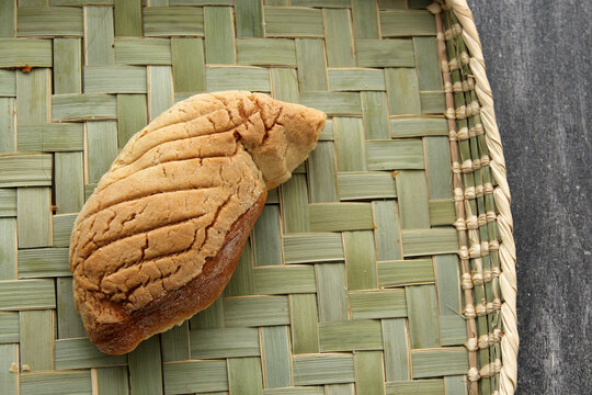 Fresh, fluffy, sugary and freshly made sweet bread stuffed with Mexican town cheese called gusano on wooden table on colored napkin accompanied by hot coffee
