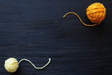 2 yellow balls of yarn on a dark wooden background. Copy space