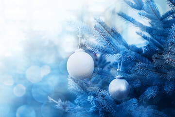 Blue christmas background with new year glass white balls on fir branch in soft selective focus, copy space, bokeh