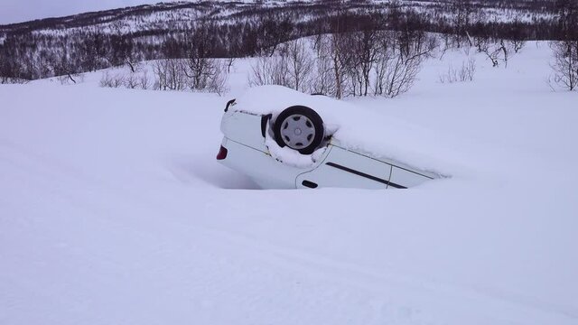 Car turned over after accident in mountains in deep snow after snowfall, back view, car rides of icy slippery mountain road, panning video