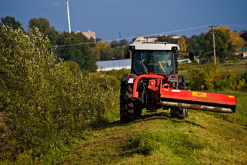 Traktor koszący trawę na terenach miejskich . Tractor mowing grass in urban areas. 