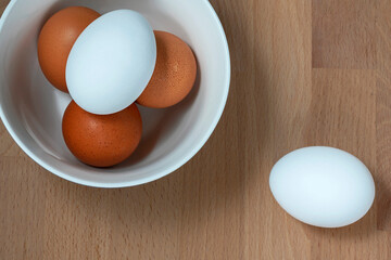 several fresh chicken eggs in a ceramic cup on a wooden background. Healthy eating concept