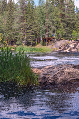 stormy mountain river with a waterfall and tourists on a pedestrian suspension bridge in Karelia, Russia