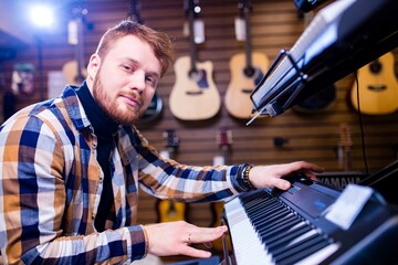 redhair ginger beard man is playing on piano in music store